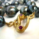 Black Tahitian pearl strand with rubies set in 18 kt. gold clasp